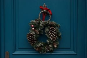 Grön julkrans med rött snöre hänger på blå dörr