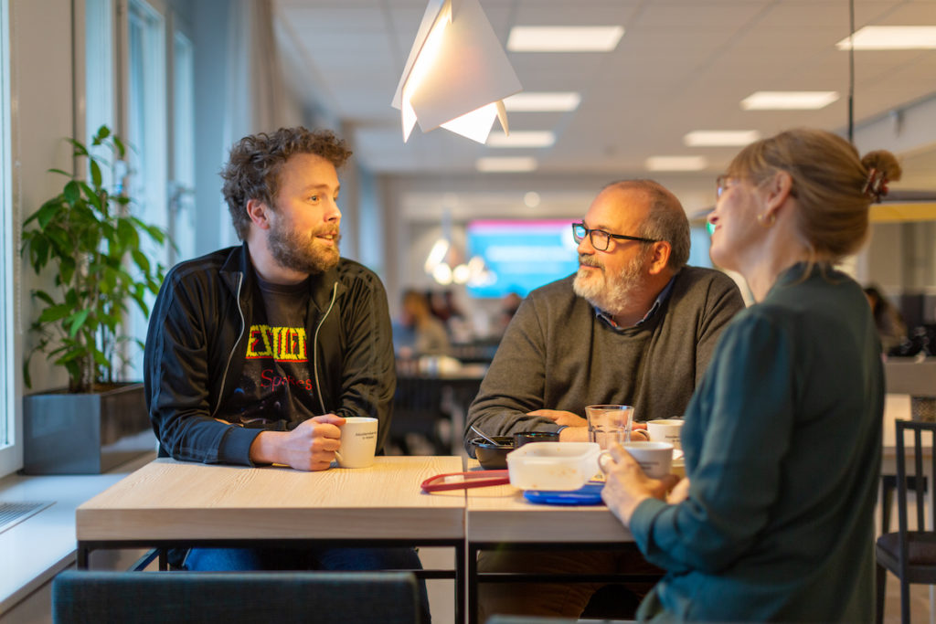 Pressbild Akademikernas a-kassa. Tre personer samtalar under en fikapaus