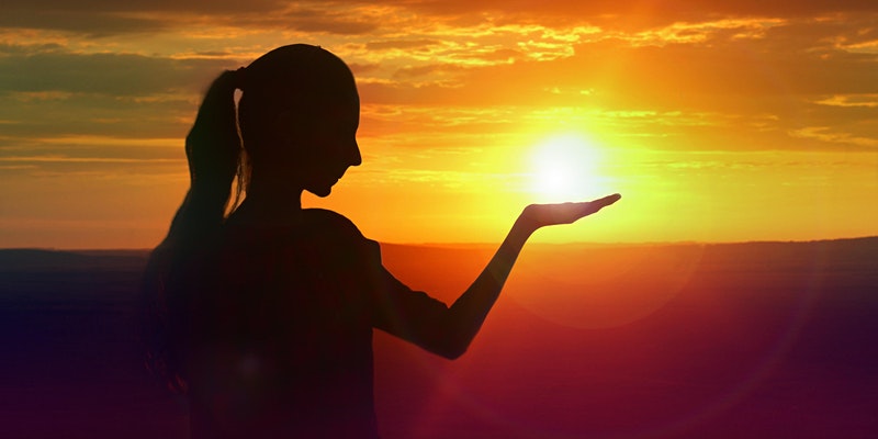 Kvinna i solnedgång, hon håller handen under solen som lyser bakom handen