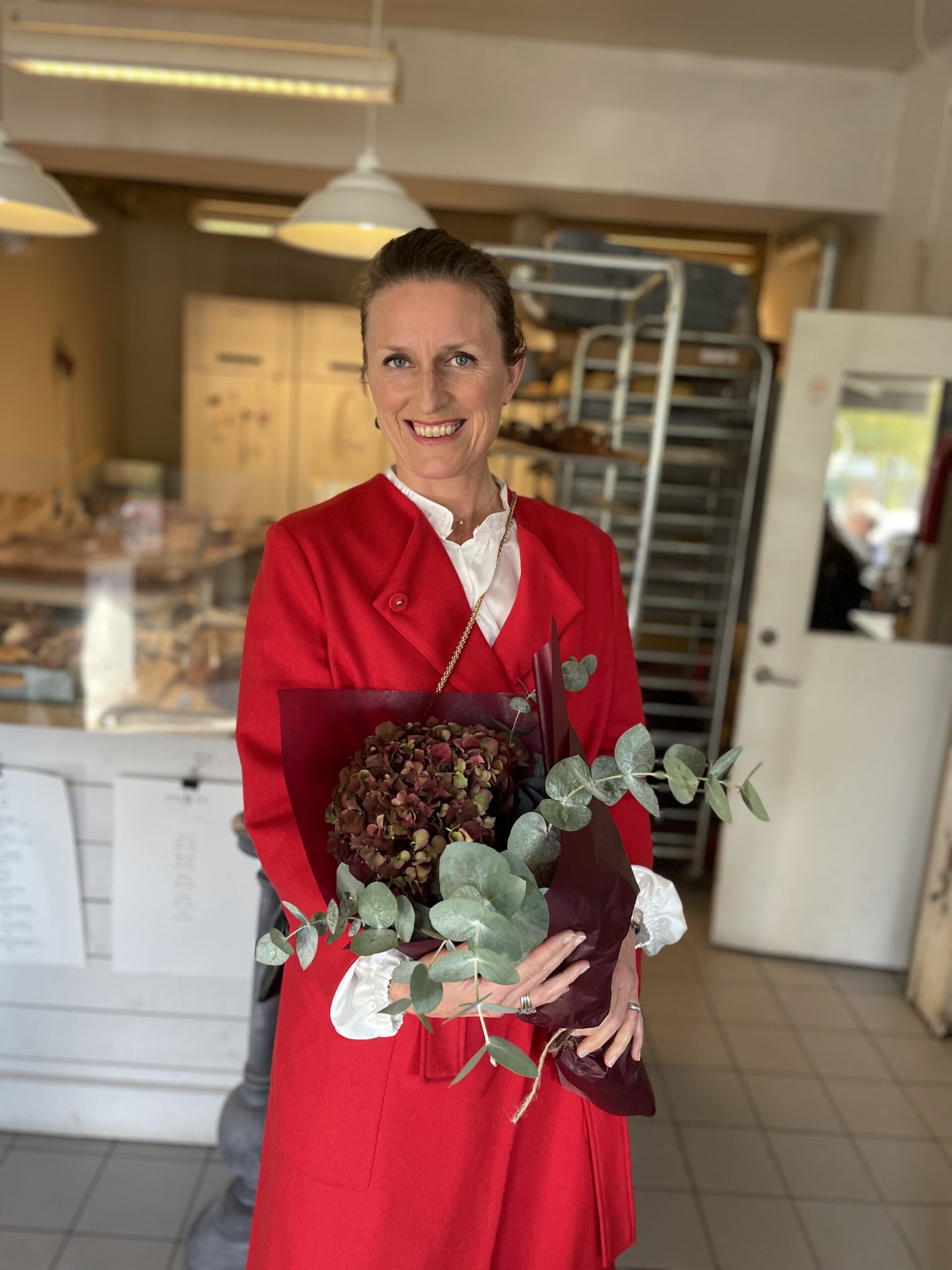 Mia Holger iklädd röd rock håller i en bukett