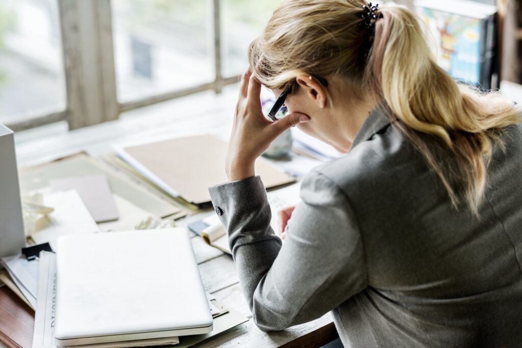 Kvinna i kostym på kontor ser stressad ut.