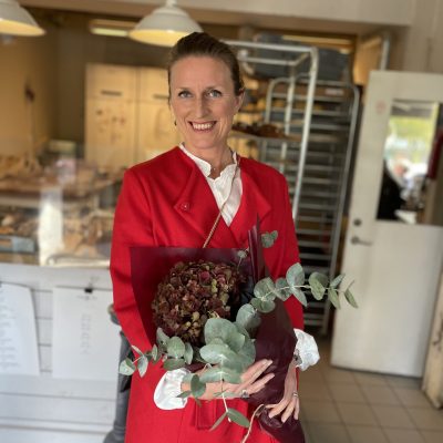 Mia Holger iklädd röd rock håller i en bukett