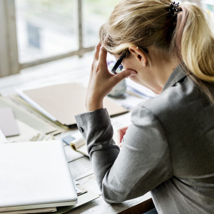 Kvinna i kostym på kontor ser stressad ut.